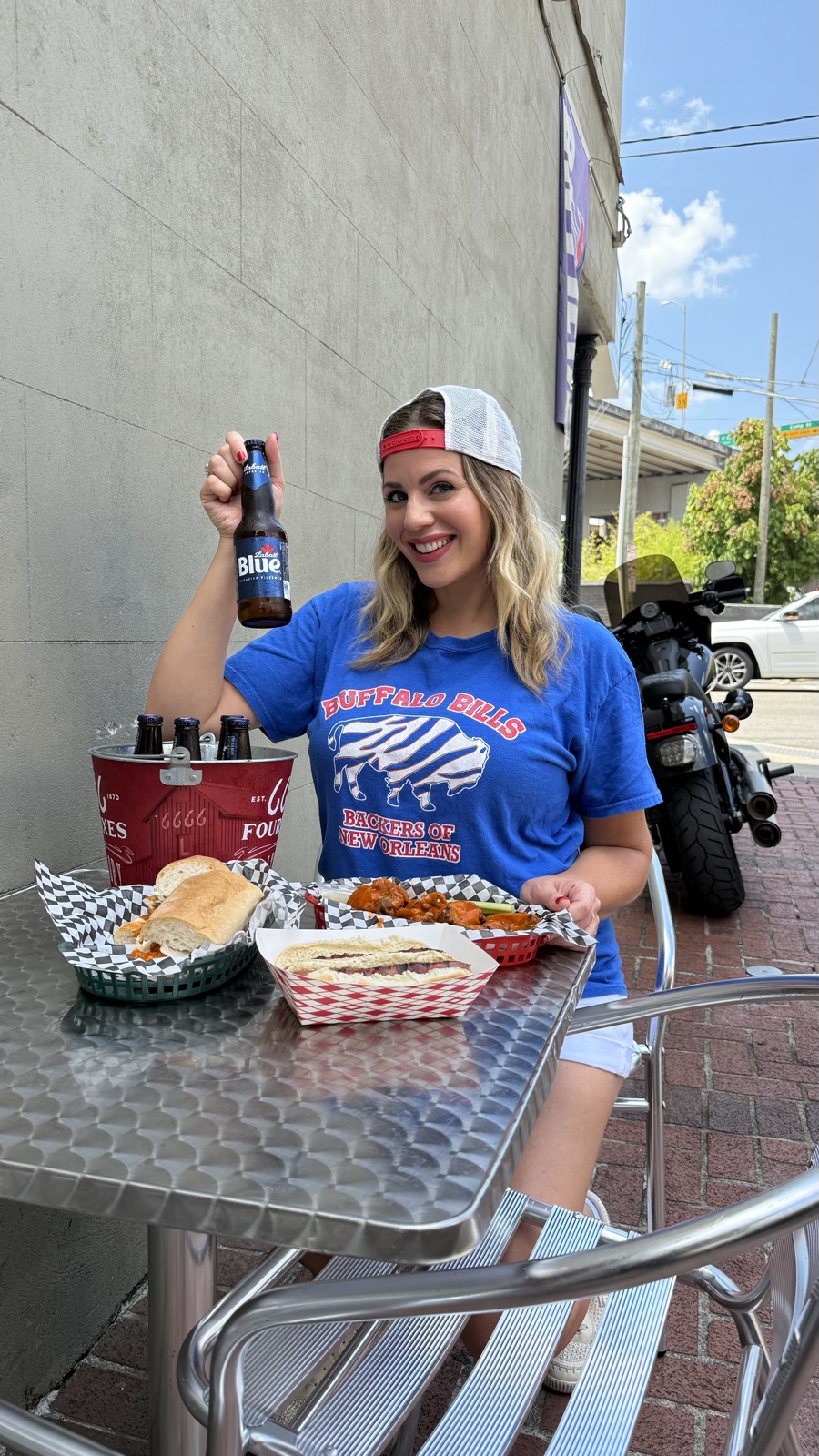 Carla in a Buffalo Bills Backers of New Orleans T-shirt, raising a Labatt Blue at a table with wings