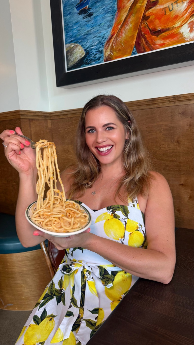 Carla twirling pasta in a lemon-print dress