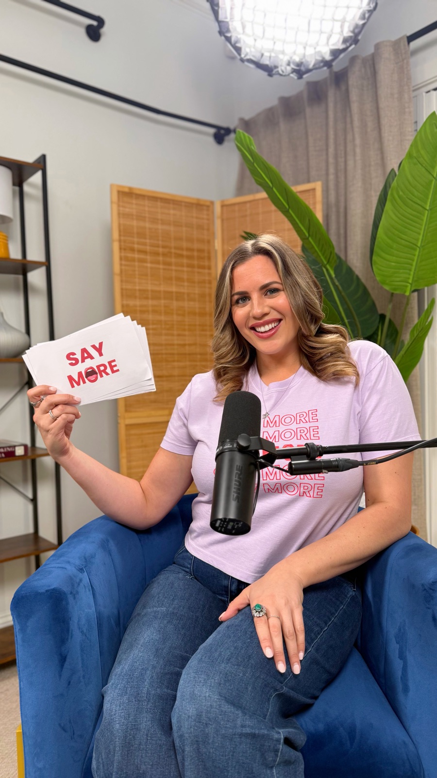 Carla with Say More cards behind a podcast microphone